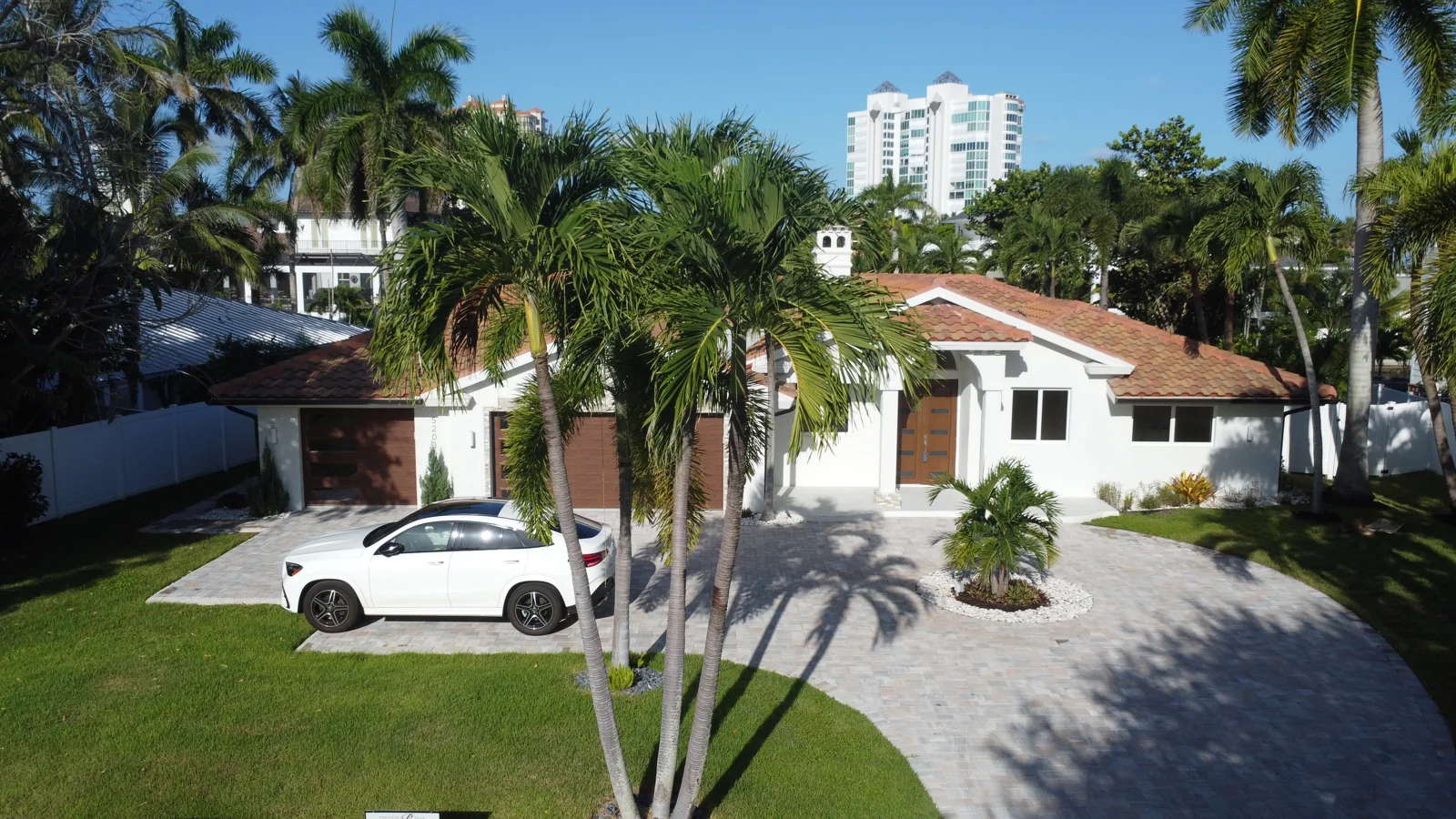 Florida home framed by palm trees, with a tile roof and circular driveway